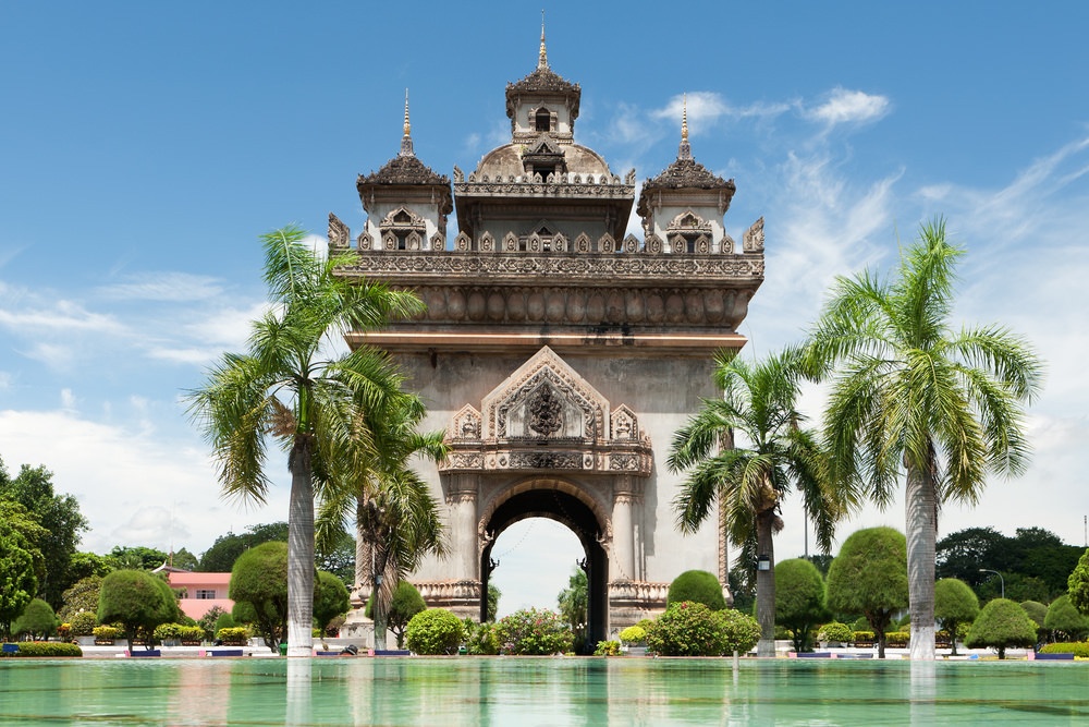 Patuxai Victory Monument with beautiful water and palm trees surrounding.